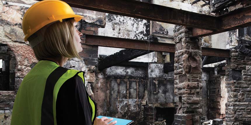 Lady in a helmet looking at fire damage