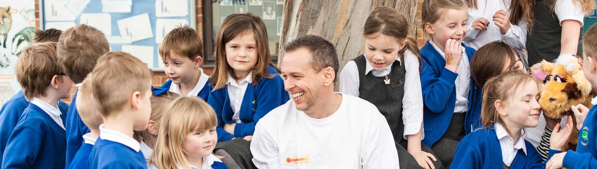 Man in Ecclesiastical top reading to group of primary school children