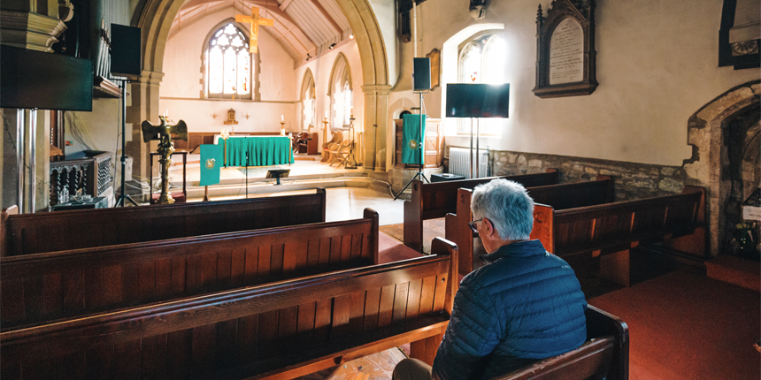A man sits alone in the pews at a small church.