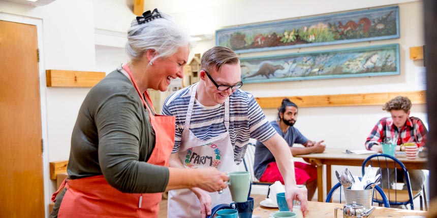 Two people volunteering in cafe and serving hot drinks